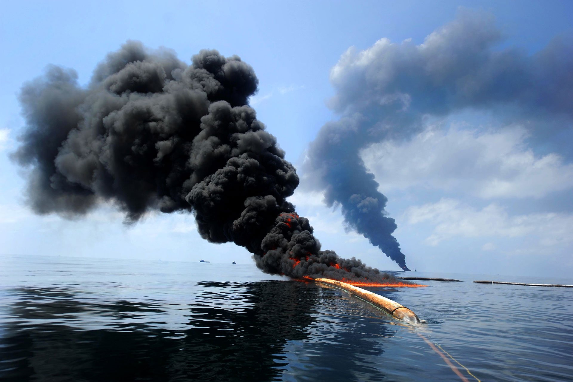Smoke rises from a fire on the surface of the ocean.