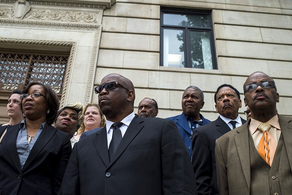 Pastor Alex C. Overton (center) stood amid water activists, a city councilman, and an attorney on the steps outside of the Genesee County Circuit Court in Flint, Michigan, after filing a lawsuit in 2015, that alleged the city had 
