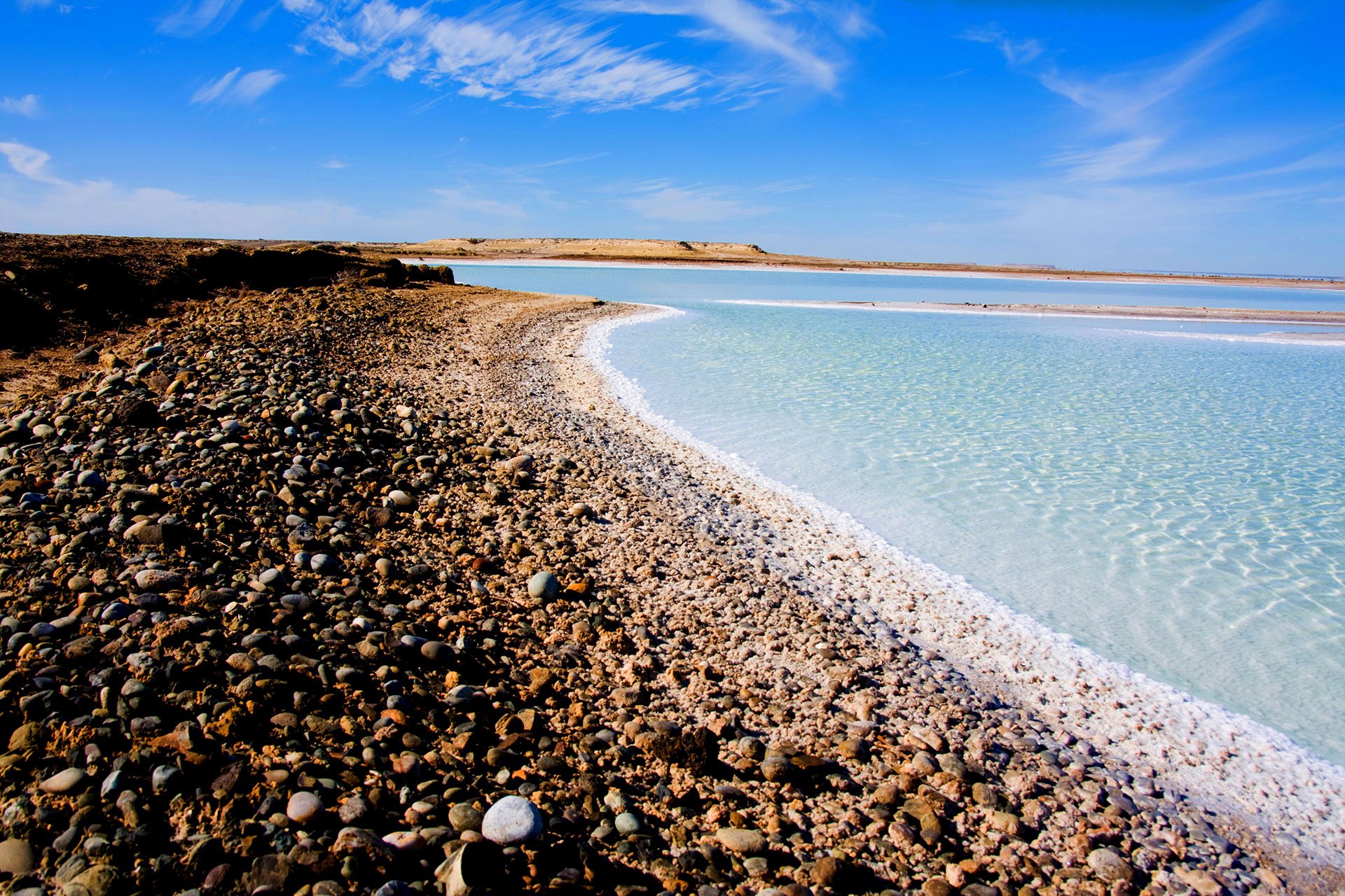 A sunny tropical beach covered in pebbles.